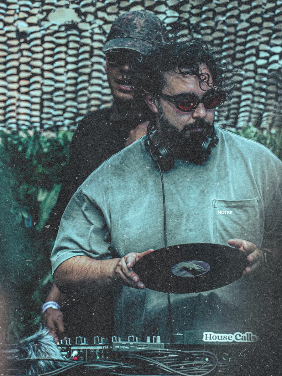 Alex Delgado at the decks, holding a vinyl record